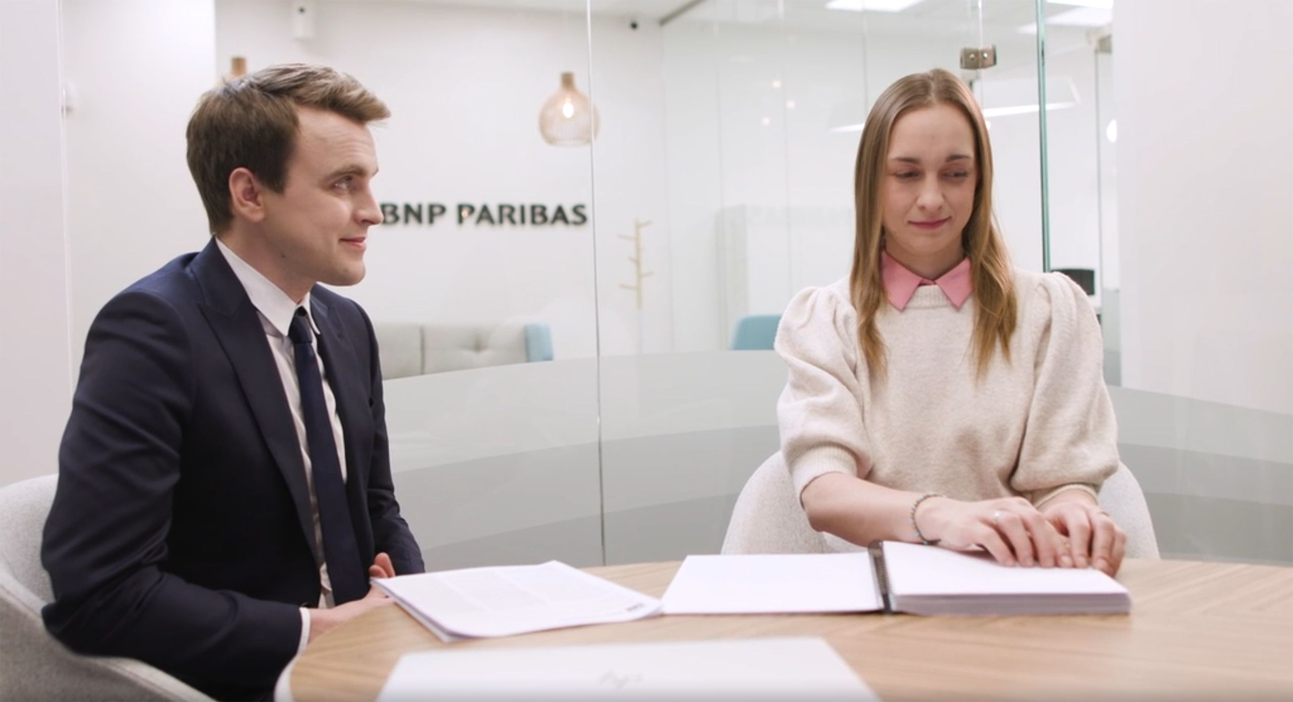 Niewidoma kobieta w oddziale banku czyta dokument w alfabecie braille'a