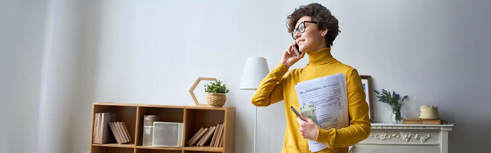 kobieta rozmawiająca przez telefon trzymająca laptopa i pieniądze