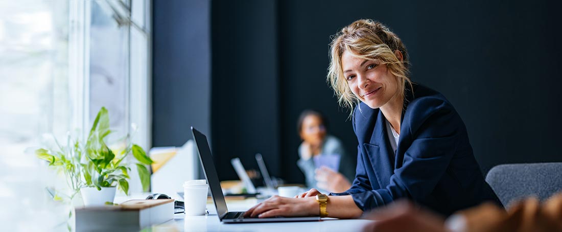 Uśmiechnięta kobieta siedzi przy biurku