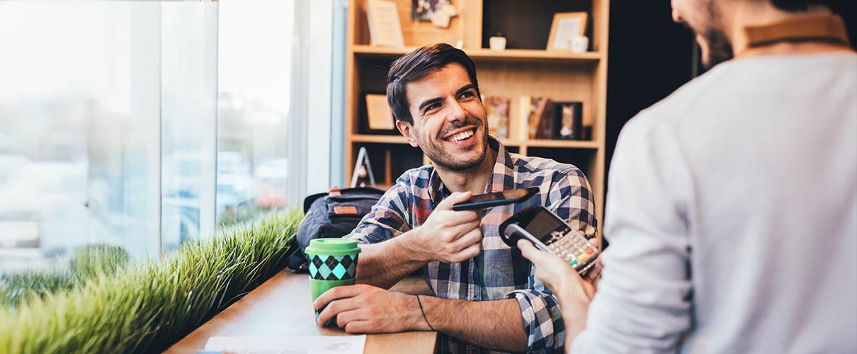 mężczyzna w kawiarni płaci za kawę telefonem