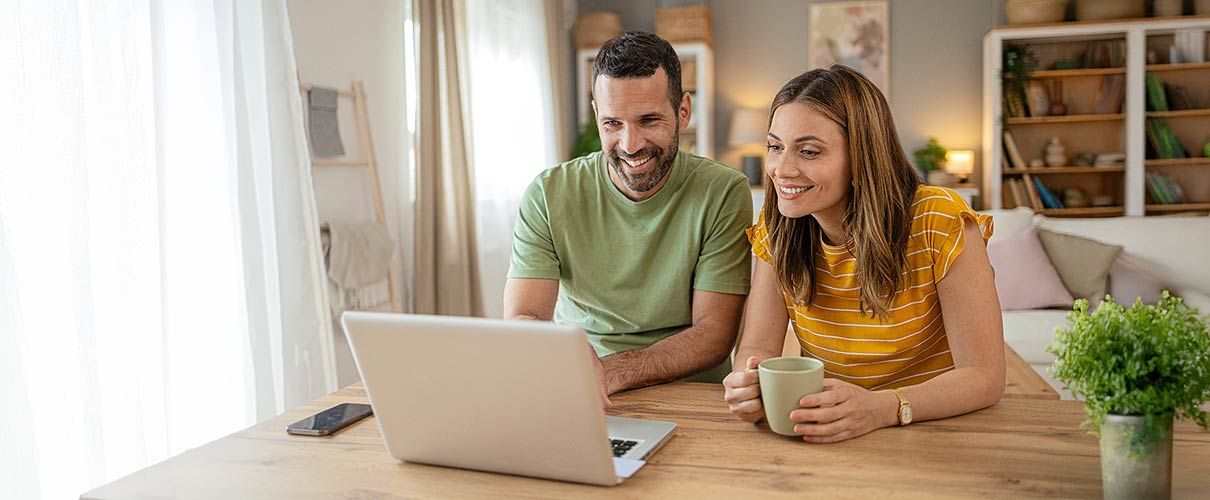 Kobieta i mężczyzna siedzą przy stole i patrzą na laptop