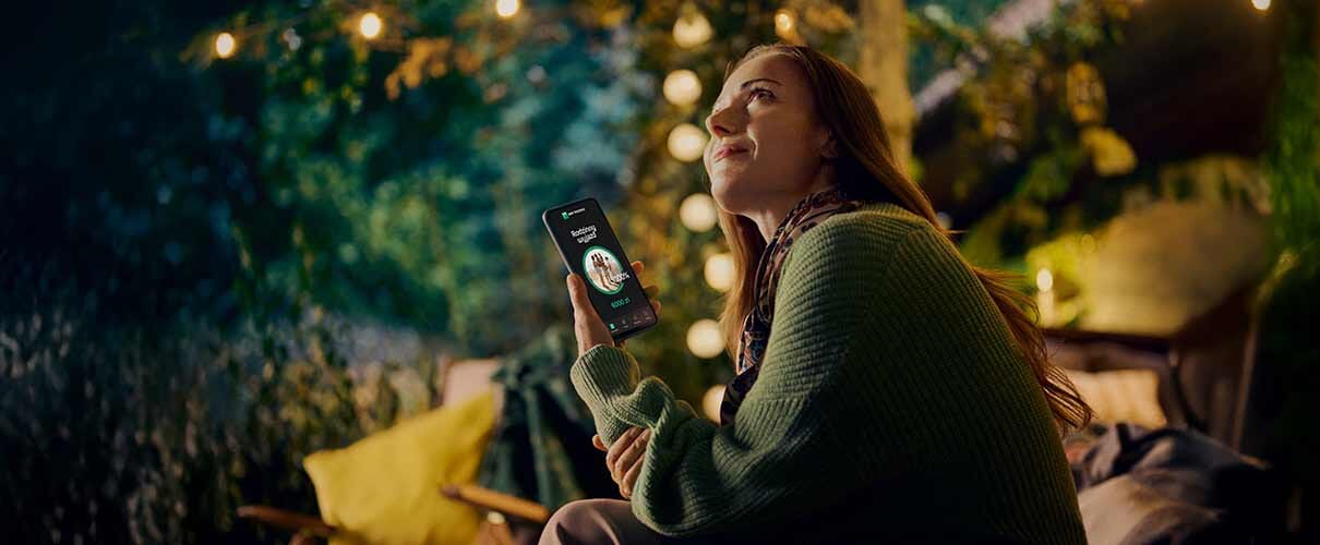 kobieta siedzi wieczorem w parku z telefonem w ręce