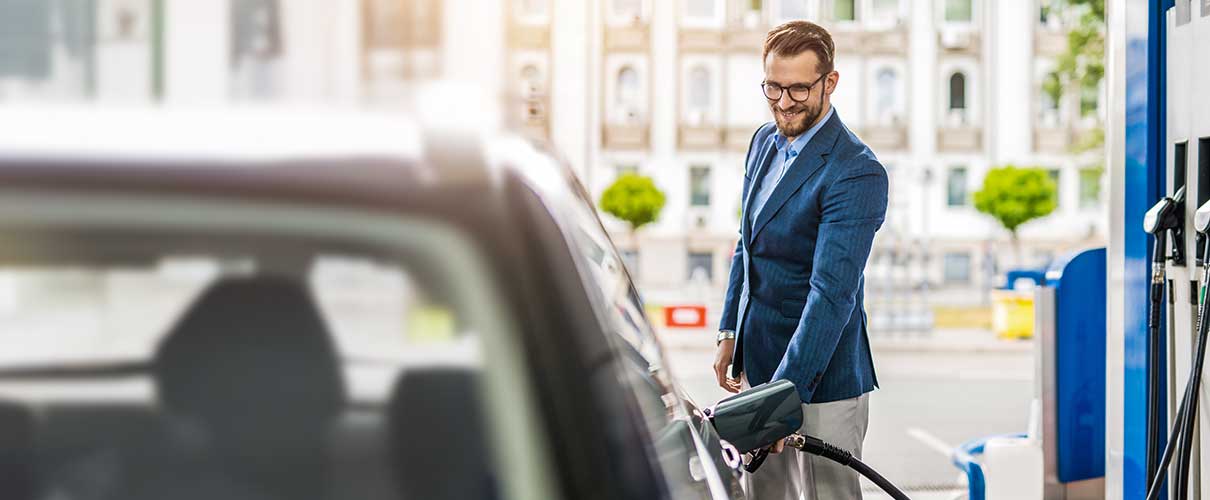 uśmiechnięty mężczyzna tankuje samochód na stacji benzynowej