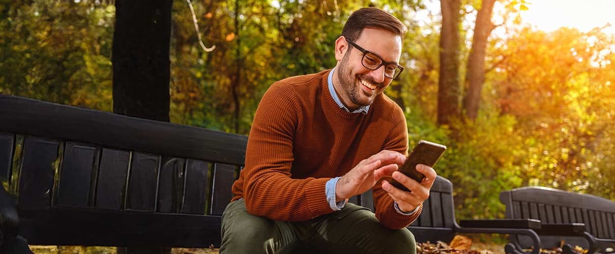 pan w parku na ławce z telefonem