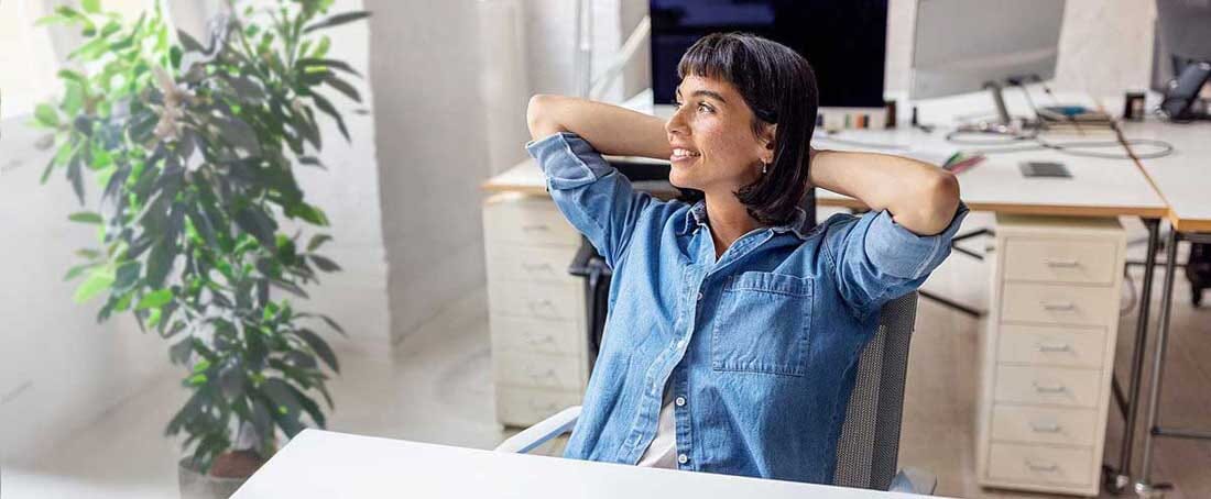 Zadowolona kobieta siedzi przy biurku