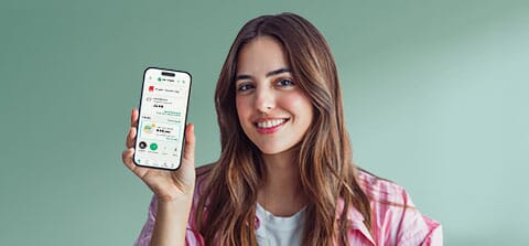 dziewczyna pokazuje telefon i funkcje aplikacji -  BLIK, oszczędności GOdreams, ubezpieczenie, kantor, opłaty za parkingi, kupno biletów na komunikację miejską i kartę w telefonie