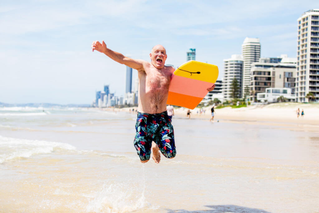 Young at heart, energetic man relaxes and enjoys beach and surf on a sunny day on an Australian beach
