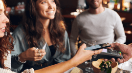 Grupa młodych ludzi w restauracji, płacąca kartą z limitem odnawialnym