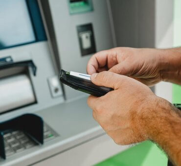 mężczyzna wpłaca pieniądze przez bankomat
