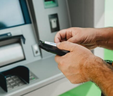 mężczyzna wpłaca pieniądze przez bankomat