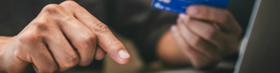 mężczyzna z laptopem, płacący kartą kredytową