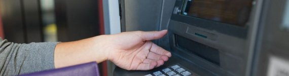 kobieta przy bankomacie, czekająca na kartę płatniczą