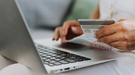 kobieta z laptopem i kartą bankową, czytająca o różnicach między kredytem a pożyczką