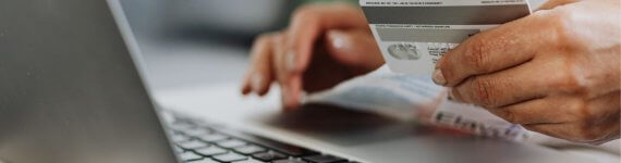 kobieta z laptopem i kartą bankową, czytająca o różnicach między kredytem a pożyczką