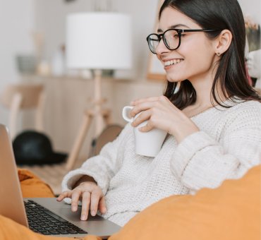 uśmiechnięta, młoda kobieta z laptopem, wnioskuje o kredyt konsolidacyjny online