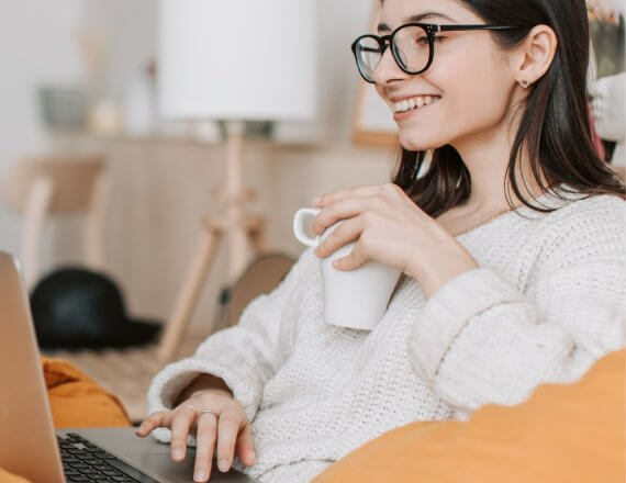 uśmiechnięta, młoda kobieta z laptopem, wnioskuje o kredyt konsolidacyjny online