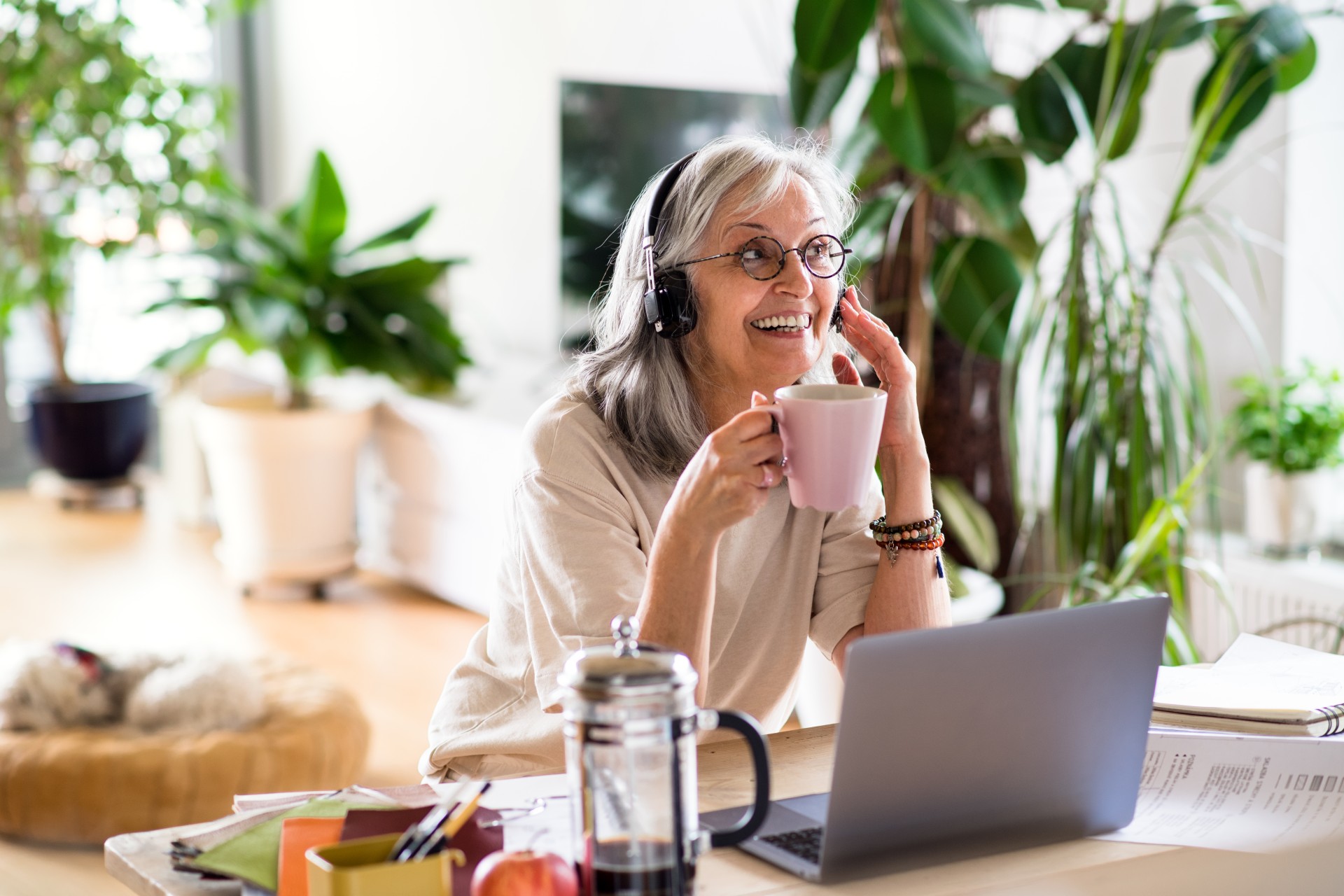 Starsza kobieta, pracownik banku z obszaru Personal Finanse siedząca przy biurku podczas pracy zdalnej w domu.