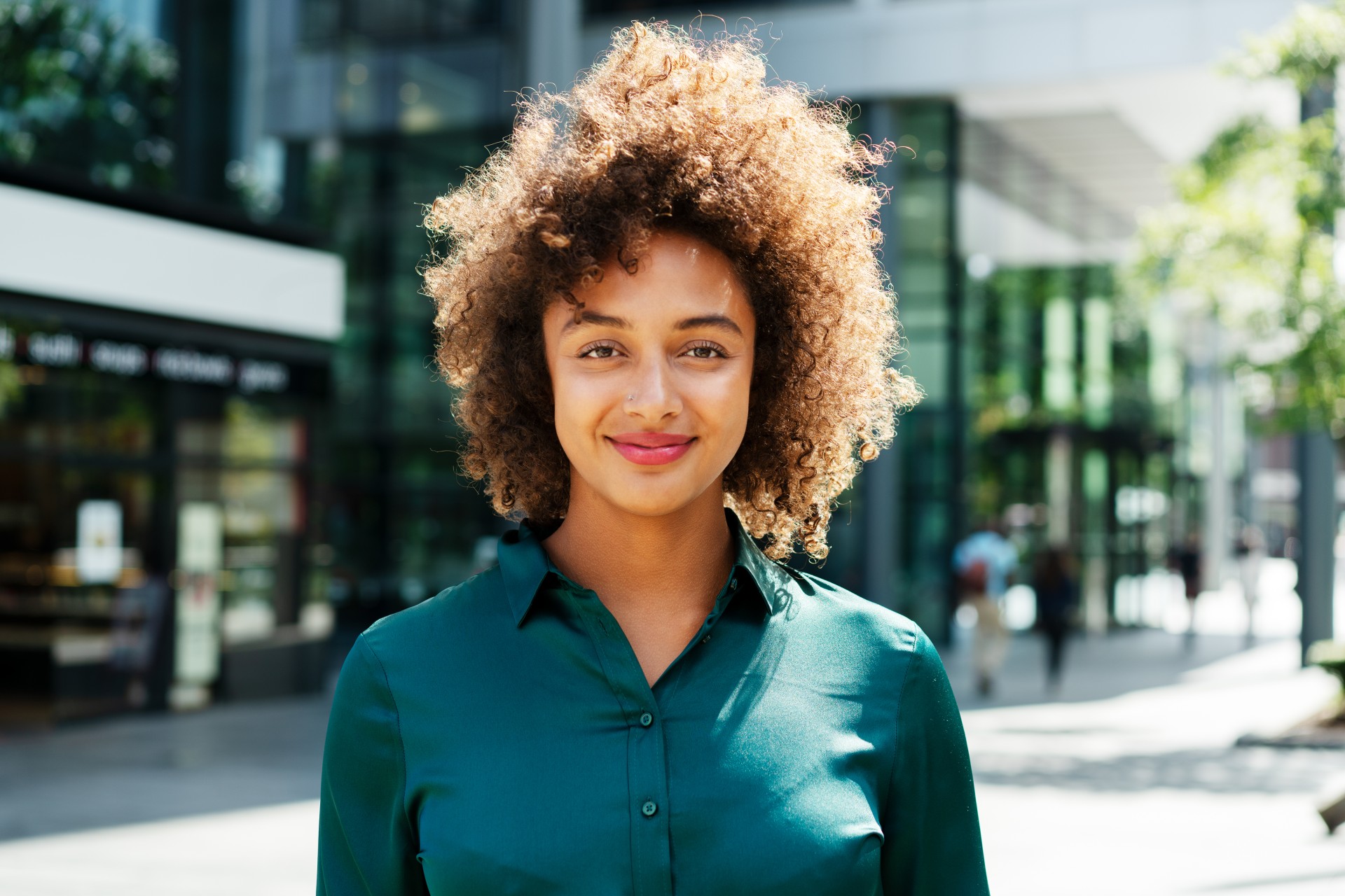 Młoda kobieta, pracownik banku z obszaru Agri&Food przed siedzibą banku.