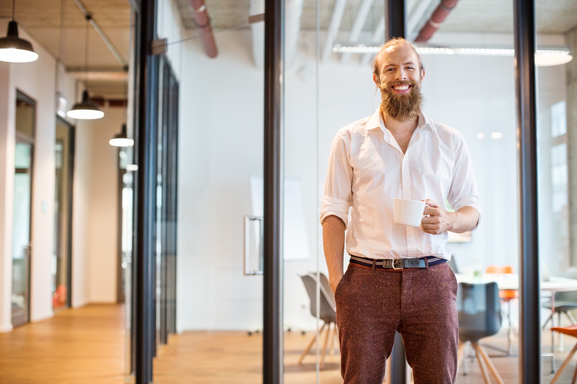 Mężczyzna, pracownik banku, stojący w biurze przed salą konferencyjną.