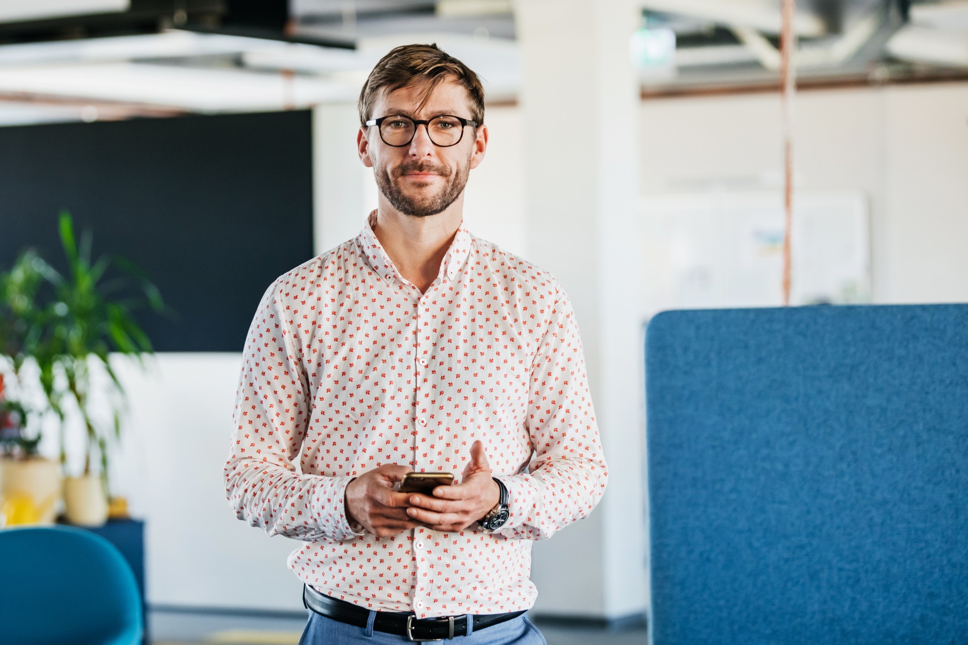 Pracownik banku w obszaru IT stoi w przestrzeni biurowej w banku.